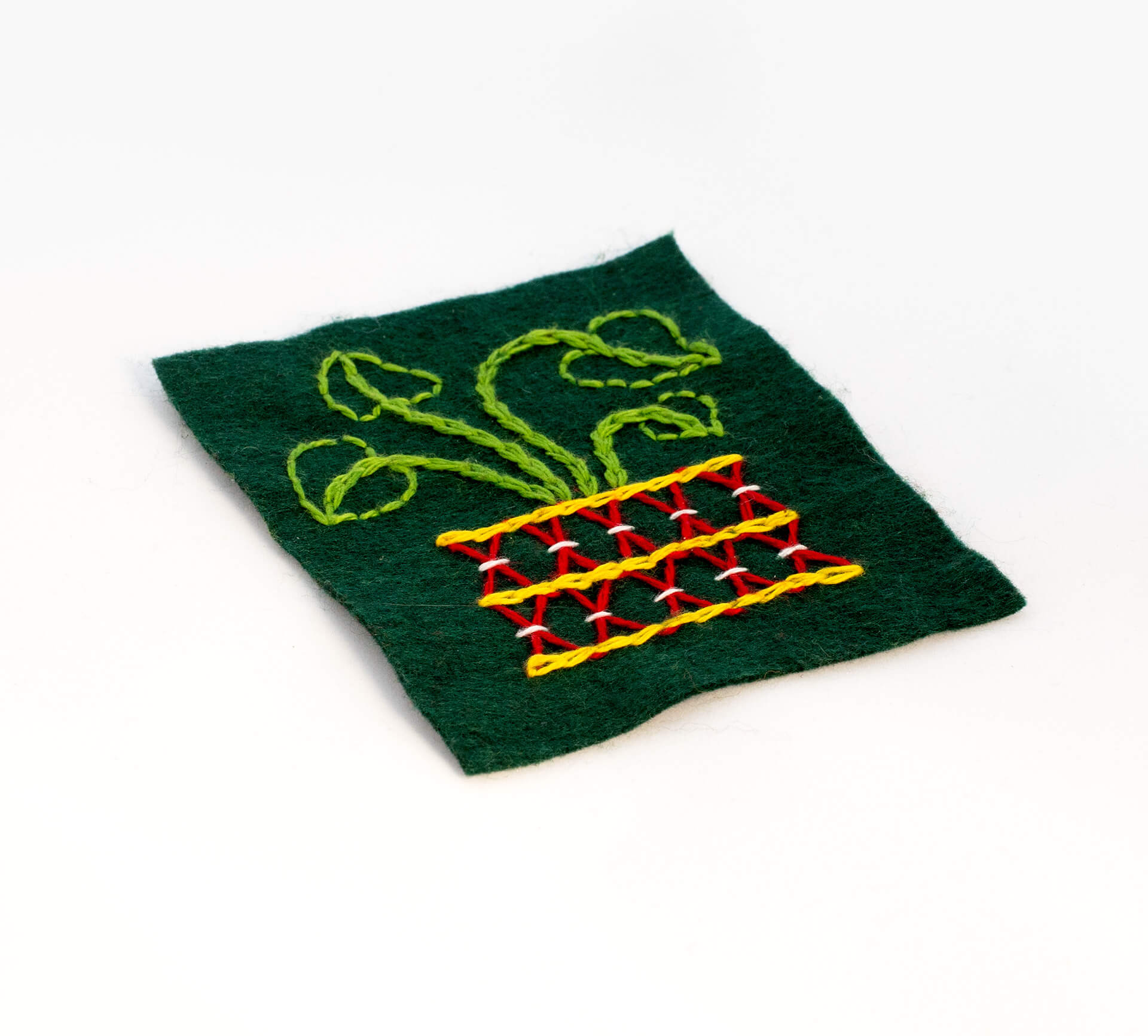 Broderi av bomullsgarn på filt, med motiv av en blomkruka